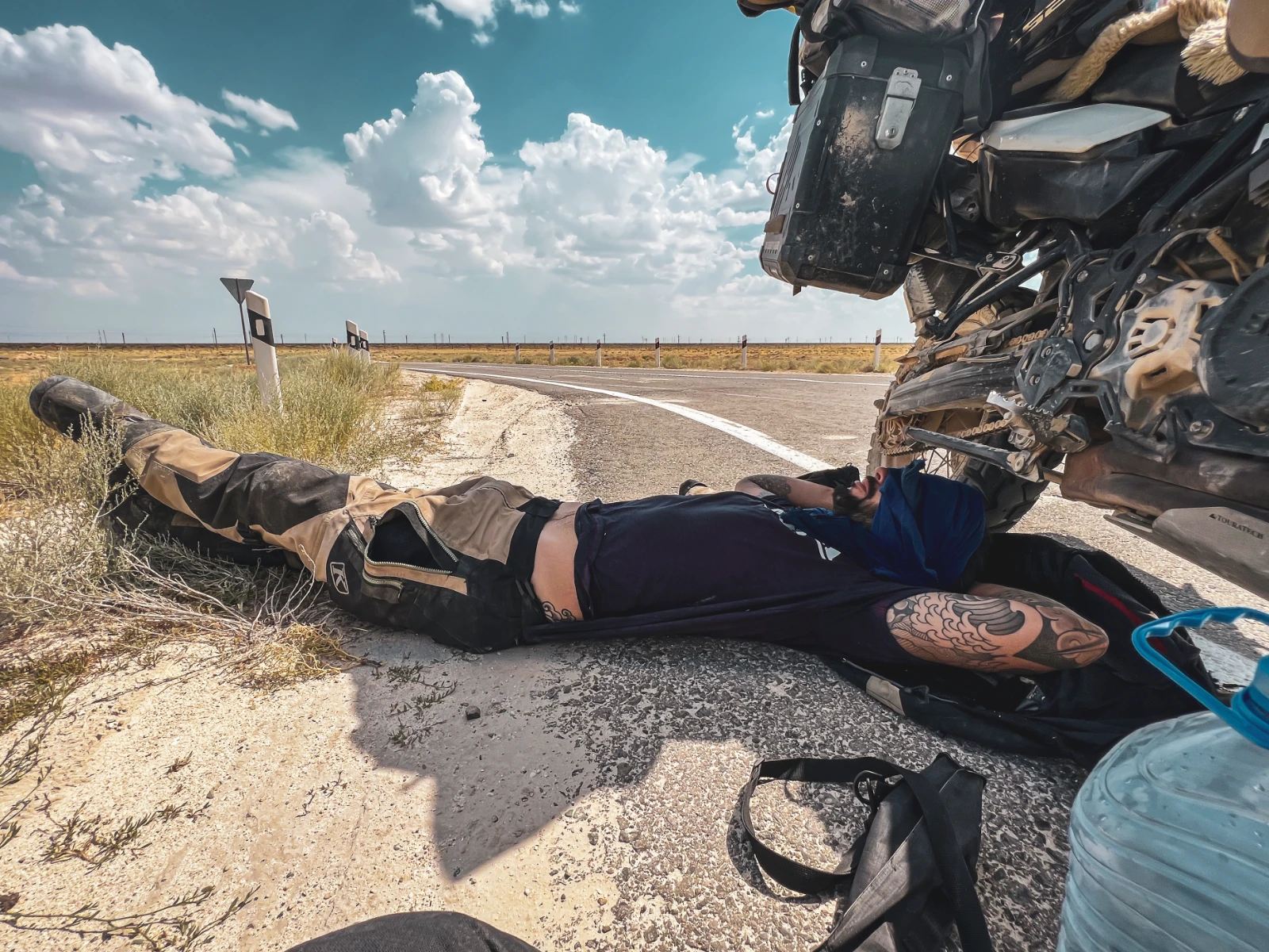 Overheated rider sheltering under motorcycle in Mangystau