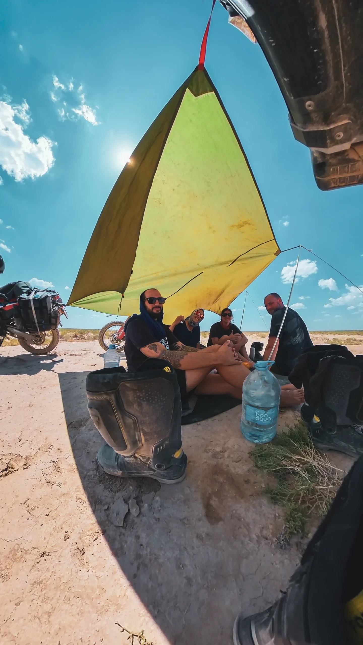 Shade solution in the Mangystau Desert — tarp strung between motorcycles