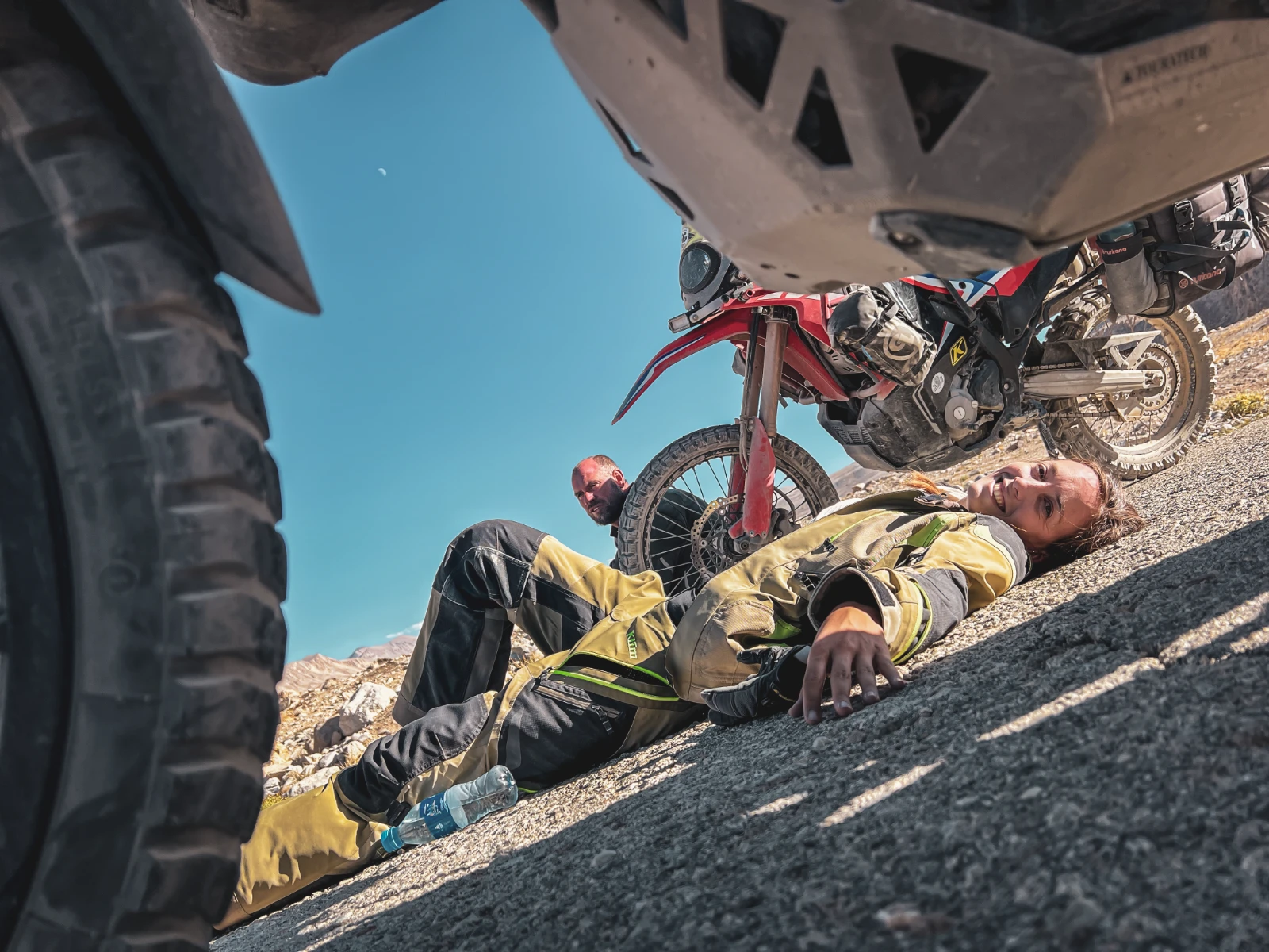 Natha resting on the ground during a break on the Pamir Highway, the road is demanding