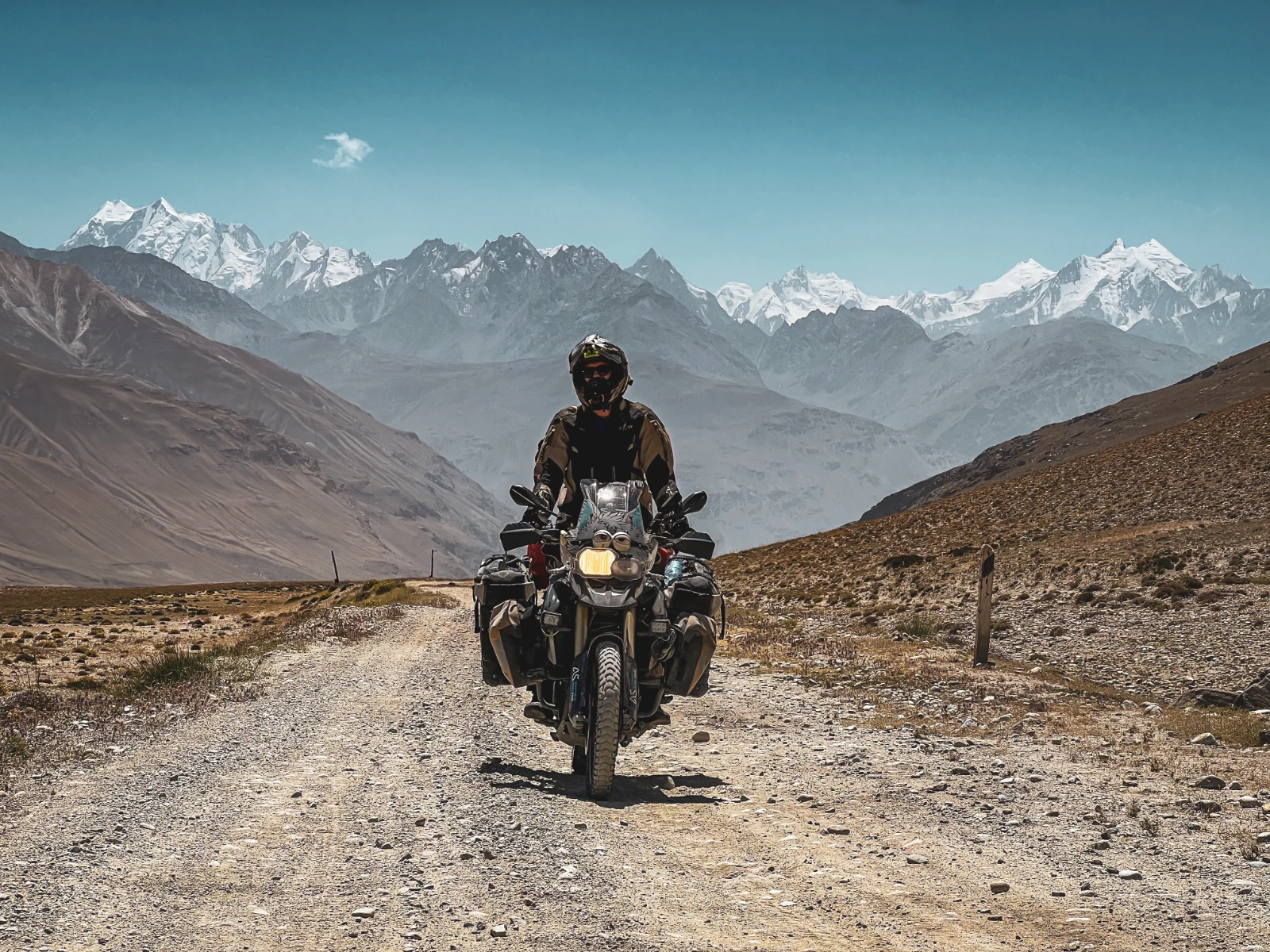 Giant Pamir mountains surrounding the motorcycle on the Wakhan corridor